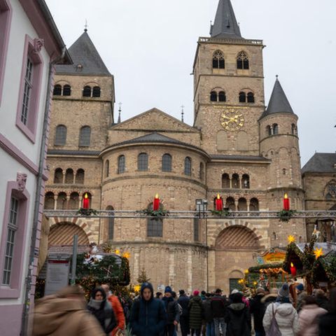 Menschen gehen von und zum Weihnachtsmarkt am Dom in Trier