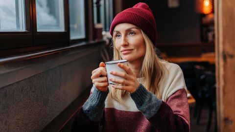 Eine Frau mit Strickmütze trinkt ein Heigetränk