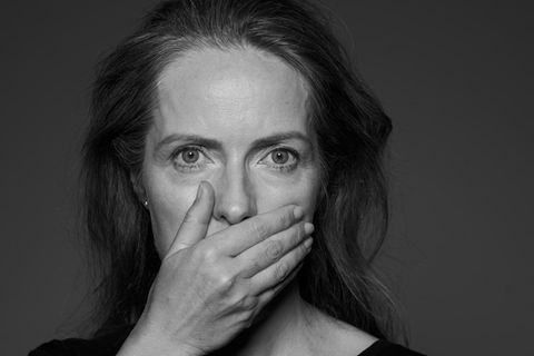 Eine Frau hält sich die Hand vor den Mund (schwarz-weiß)