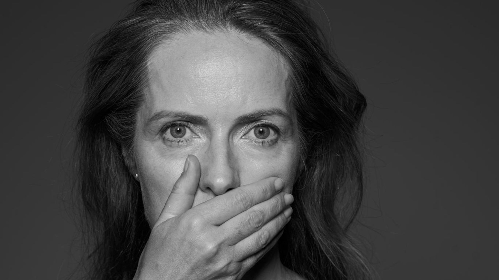 Eine Frau hält sich die Hand vor den Mund (schwarz-weiß)