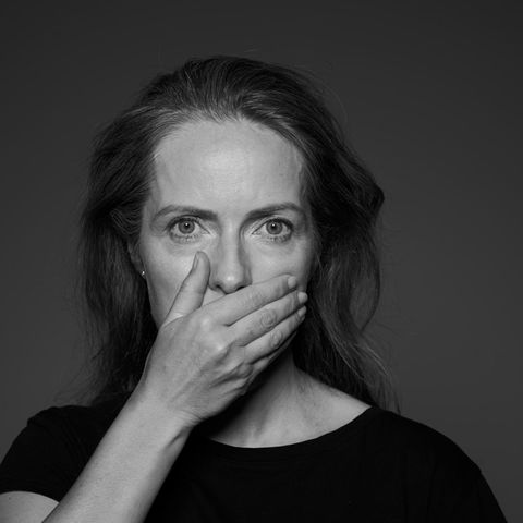 Eine Frau hält sich die Hand vor den Mund (schwarz-weiß)