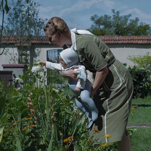 Sandra Hüller, wie sie mit einem Kleinkind im Arm Blumen betrachtet