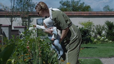 Sandra Hüller, wie sie mit einem Kleinkind im Arm Blumen betrachtet