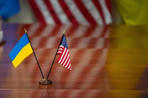 Die Flaggen der Ukraine und der USA stehen zusammen auf einem Tisch