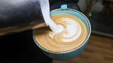 Milch wird in eine Tasse Kaffee gekippt