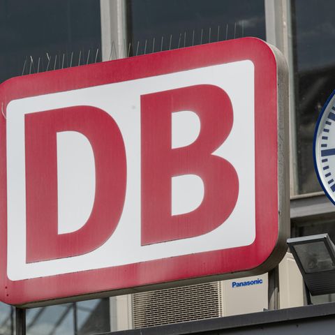 Eine Uhr hängt neben dem Logo der Deutschen Bahn am Eingang zum Münchner Hauptbahnhof