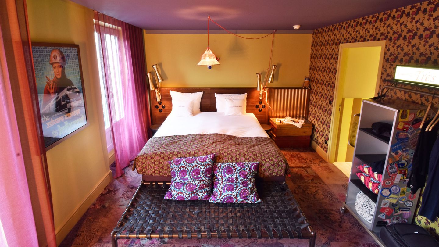 Ein Balkonzimmer im vierten Stock: Warme Farbtöne und eine eklektische Mischung aus Ornamenten und floralen Motiven mit dem offenen Trolley als Kleiderschrank.