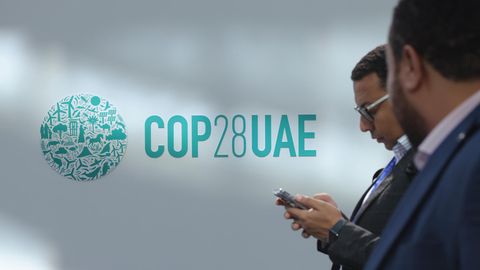 Zwei Männer in Anzügen laufen am Logo der Klimakonferenz COP28 in Dubai vorbei