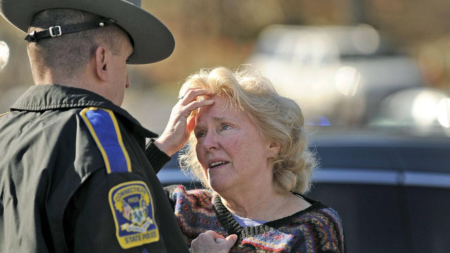 Eine aufgebrachte Frau spricht nach dem Amoklauf an der Sandy Hook Grundschule mit einem Polizeibeamten