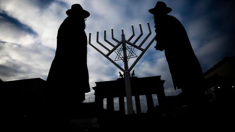 Zwei jüdische Männer mit Hüten stehen vor einem Chanukka Leuchter der vor dem Brandenburger Tor in Berlin aufgestellt wurde