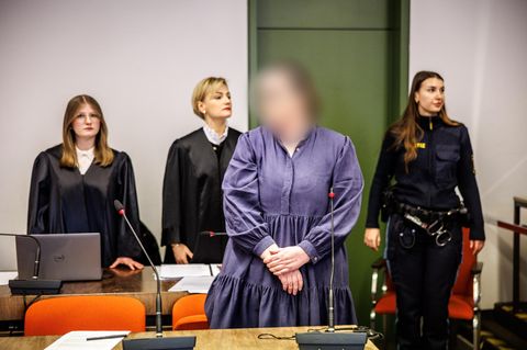 Die Angeklagte Andrea Tandler (m.) steht zu Prozessbeginn an ihrem Platz im Gerichtssaal