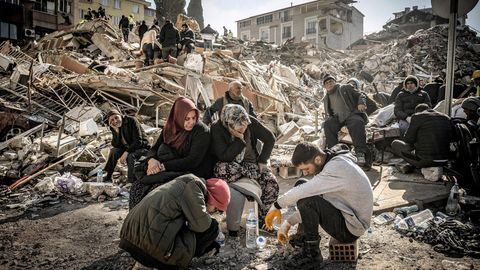 Menschen sitzen in den Trümmern ihrer vom Erdbeben zerstörten Häuser