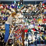 Frau steht auf einer Leiter vor einer großen Wand voller Stoffrollen