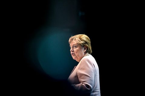 Angela Merkel sitzt auf einem Sofa, neben ihr stehen Blumen