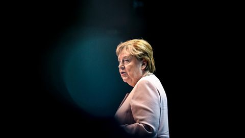 Angela Merkel sitzt auf einem Sofa, neben ihr stehen Blumen