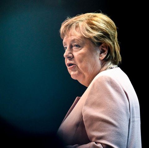 Angela Merkel sitzt auf einem Sofa, neben ihr stehen Blumen