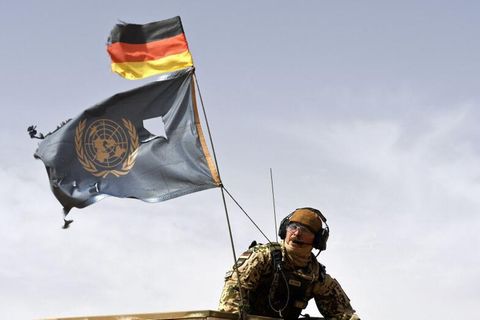 Ein Bundeswehrsoldat mit deutscher und UN-Flagge beim Einsatz in Mali