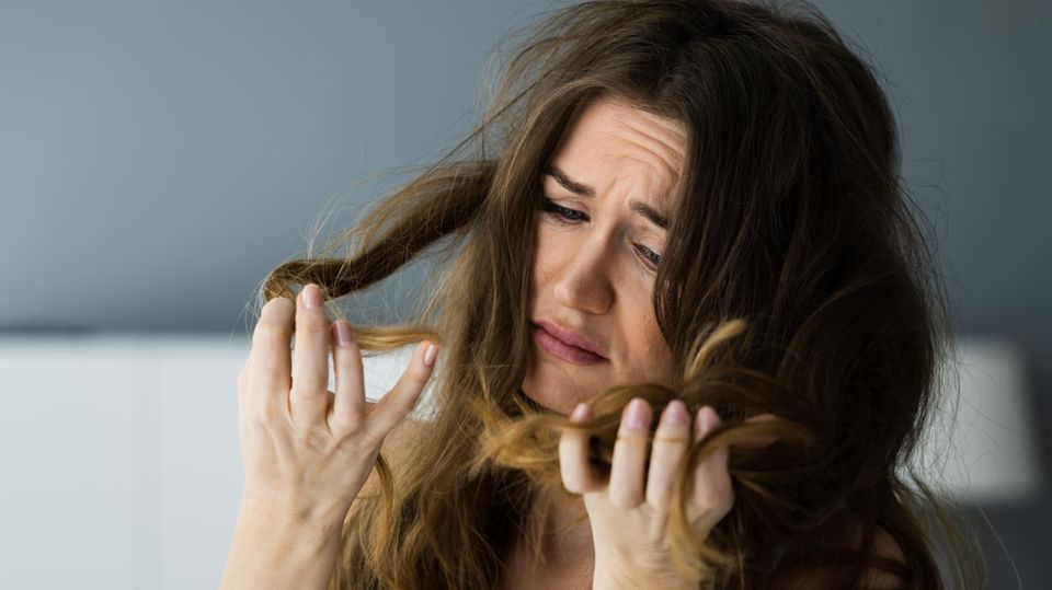 Frau schaut traurig auf ihre Haare