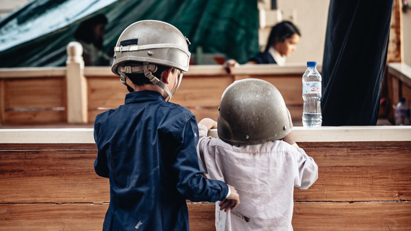 Zwei Kinder mit Helmen stehen am Flughafen in Kabul. Laut einer Studie leben fast eine halbe Milliarde Kinder in Kriegsgebieten