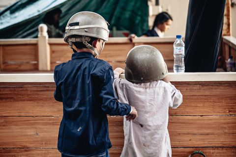 Zwei Kinder mit Helmen stehen am Flughafen in Kabul. Laut einer Studie leben fast eine halbe Milliarde Kinder in Kriegsgebieten