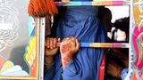 Eine Frau mit blauer Burka fährt in einem bunt bemalten Bus
