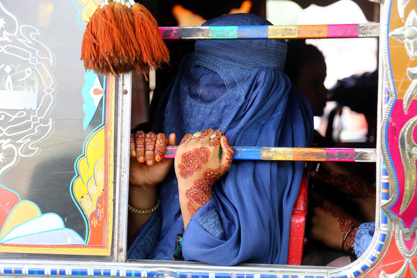 Pakistan Eine Frau mit blauer Burka fährt in einem bunt bemalten Bus
