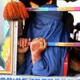 Eine Frau mit blauer Burka fährt in einem bunt bemalten Bus