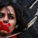 Eine Frau mit zugeklebtem Mund und schlinge um den Hals, auf einem "woman, life, freedom" protestmarsch