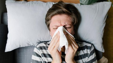 Mann schnäuzt sich die Nase