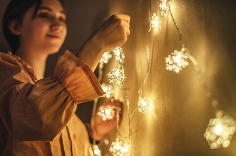 EIne Frau hängt Lichterketten auf