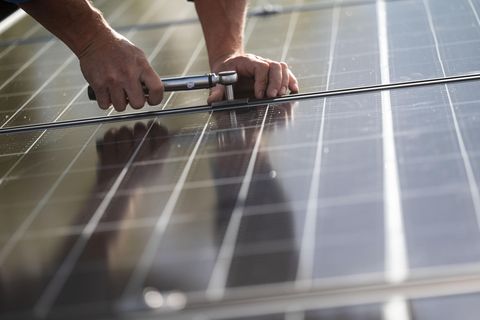 Mitarbeiter einer Firma montieren Photovoltaikmodule auf dem Dach eines Wohnhauses