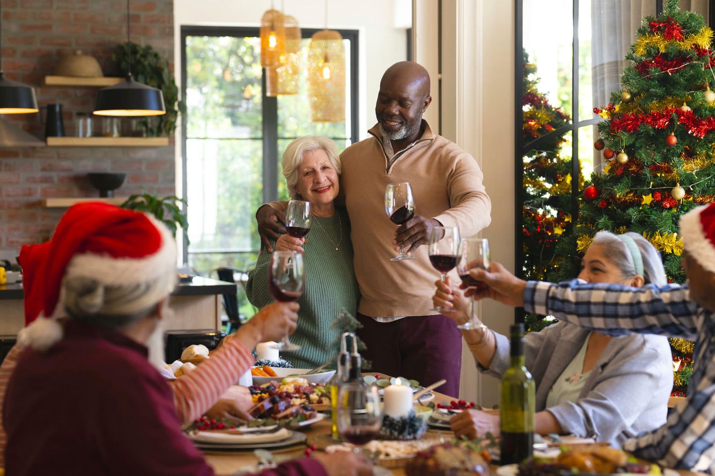 Gäste beim Weihnachtsessen prosten sich mit Rotwein zu