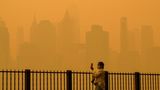 New York, USA.  Eine Frau schützt sich mit einer Maske vor dem Schleier, der die US-Metropole benebelt. Wegen der heftigen Waldbrandsaison in diesem Jahr, hat sich der Dunst über die kanadische Grenze hinweg ausgebreitet. Dadurch schossen auch die Smogwerte in die Höhe: Laut Klimaforscher Marschall Burke von der Stanford University soll die Luftbelastung die zwischen 2006 und 2022 gemessenen Höchstwerte überschritten haben.