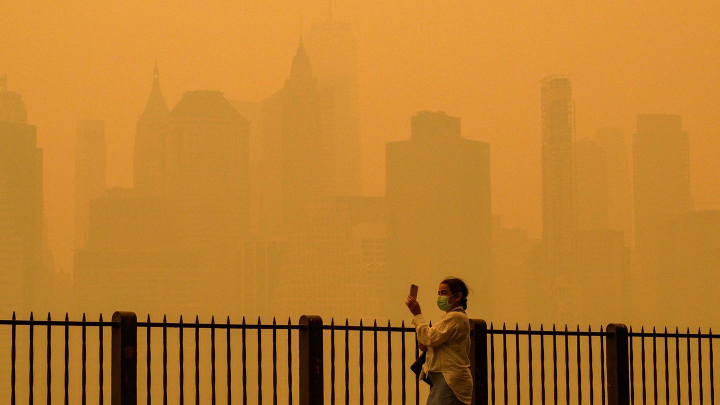 New York, USA.  Eine Frau schützt sich mit einer Maske vor dem Schleier, der die US-Metropole benebelt. Wegen der heftigen Waldbrandsaison in diesem Jahr, hat sich der Dunst über die kanadische Grenze hinweg ausgebreitet. Dadurch schossen auch die Smogwerte in die Höhe: Laut Klimaforscher Marschall Burke von der Stanford University soll die Luftbelastung die zwischen 2006 und 2022 gemessenen Höchstwerte überschritten haben.