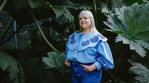Körper-Aktivistin Melodie Michelberger mit hellblauer Bluse vor Blattgrün