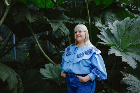 Körper-Aktivistin Melodie Michelberger mit hellblauer Bluse vor Blattgrün
