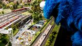 Das Krümmelmonster schaut von oben auf eine Miniatur von dem Fernsehstudio in dem die Sesamstraße produziert wird