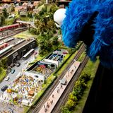 Das Krümmelmonster schaut von oben auf eine Miniatur von dem Fernsehstudio in dem die Sesamstraße produziert wird