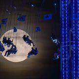 Besucher des Oktoberfestes auf einer Attraktion mit dem Mond im Hintergrund