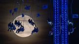 Besucher des Oktoberfestes auf einer Attraktion mit dem Mond im Hintergrund