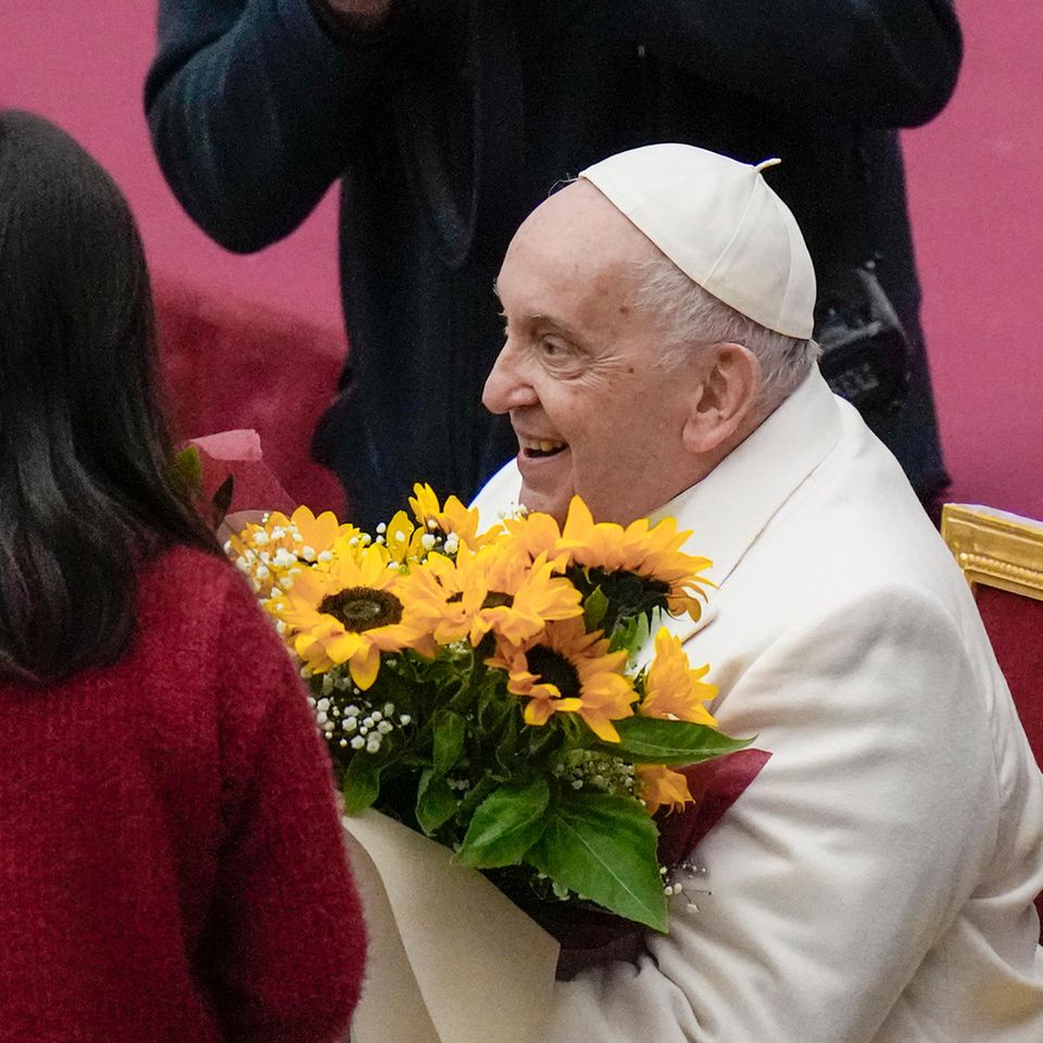 Vatikanstadt, Vatikan. Papst Franziskus hat seinen 87. Geburtstag an diesem Sonntag gemeinsam mit zahlreichen Kindern im Vatikan gefeiert. Familien, die von einer vatikanischen Kindersozialeinrichtung unterstützt und betreut werden, trafen das Oberhaupt der katholischen Kirche in der Audienzhalle des Kirchenstaates, um dem Jubilar zu gratulieren. Dies ist seit seiner Wahl zum Papst 2013 Tradition. Franziskus blies gemeinsam mit einigen Kindern die Kerzen auf seiner Geburtstagstorte aus und ließ sie daraufhin von ihr kosten. Die Familien gratulierten dem Pontifex und überreichten ihm zudem Blumen.