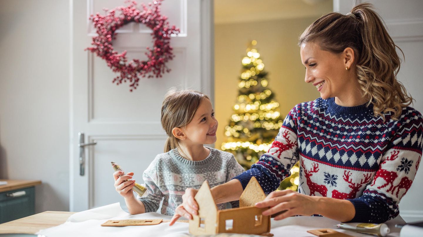 Eine Mutter schmückt mit ihrer Tochter ein Lebkuchenhaus