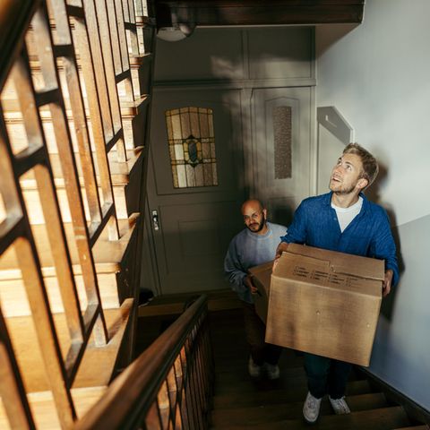 Ein Mann trägt einen Umzugskarton durch ein Treppenhaus