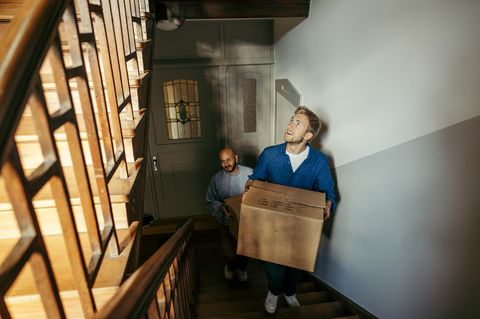 Ein Mann trägt einen Umzugskarton durch ein Treppenhaus