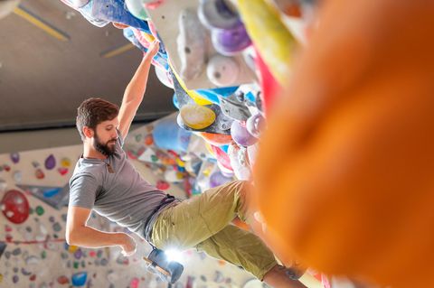 Geschenke für Kletterer: Junger Mann klettert in einer Kletterhalle