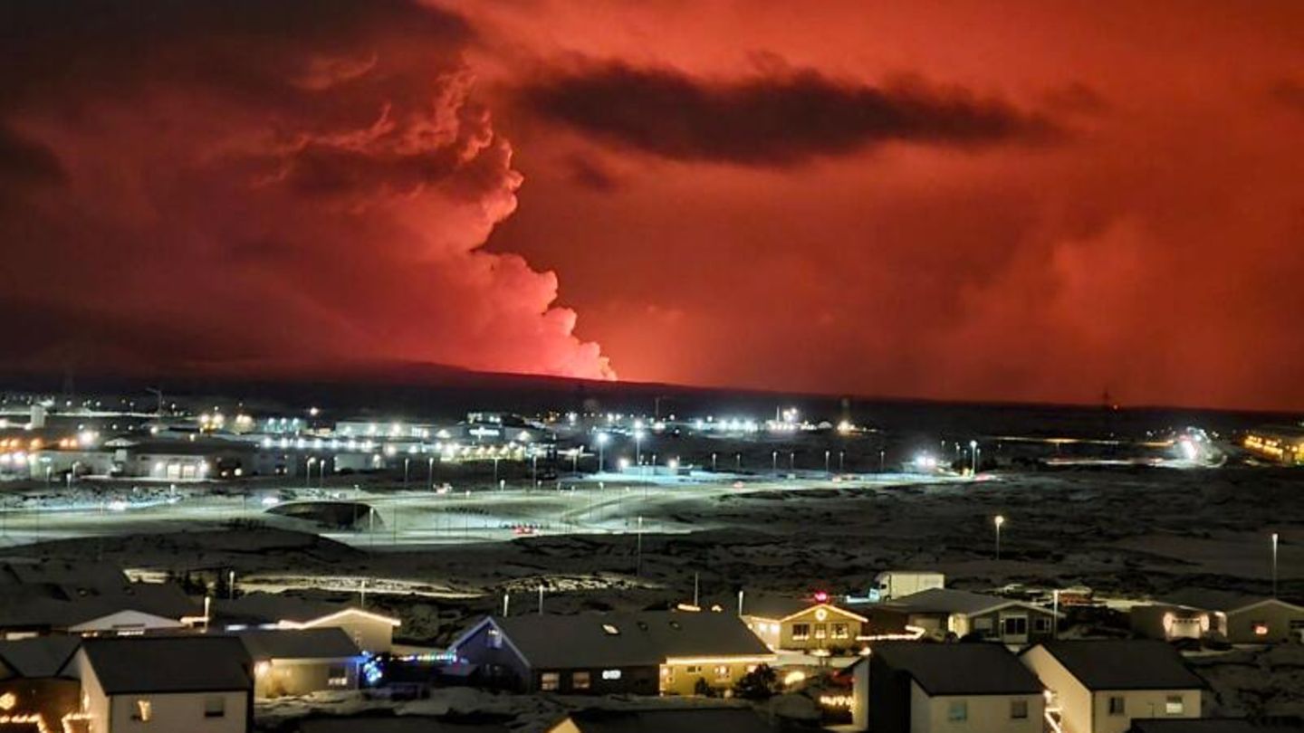 Häuser in der Ortschaft Hafnarfjörður sind zu sehen, während in der Ferne Rauch aufsteigt