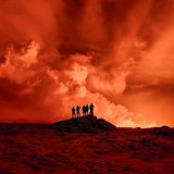 Anwohner beobachten die Rauchschwaden und die orangefarbene Färbung des Nachthimmels durch die Lava