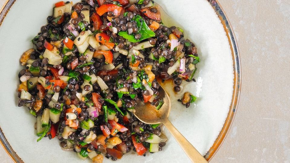 BUNTER LINSENSALAT  Mit Granatapfel & Kreuzkümmel  Dieses Rezept ist ein Allroundtalent: Die Basis lässt sich mit verschiedenen Gemüsen, auch Ofengemüsen, Kräutern und Früchten immer wieder neu variieren. Außerdem lassen sich die Linsen sehr gut vorbereiten, um den Salat zum Beispiel mit zum Grillabend oder zur Gartenparty bei Freunden zu bringen. Ein perfekter Kandidat fürs bunte Food­- oder Tisch-­Büfett.  Zutaten für 4 Portionen  Für die Linsen: 300 g Belugalinsen, Salz, 3 EL Granatapfeldicksaft  Für den Salat: 1 rote Zwiebel, 1 große Salatgurke, 4 mittelgroße Rispentomaten, 5 EL gehackte glatte Petersilie, 4 EL geröstete Walnusskerne  Für die Vinaigrette: 5 EL Olivenöl, Saft von 1⁄2 Zitrone, 1 Msp. Zitronenabrieb, 2 EL Ahornsirup, 2 Msp. gemahlener Kreuzkümmel, 1 Msp. gemahlener Rauchpaprika, frisch gemahlener schwarzer Pfeffer     Zubereitung:  Die Belugalinsen in der doppelten Menge gesalzenem Wasser rund 20 Minuten bei kleiner Hitze köcheln lassen. Aufpassen, dass die Linsen nicht zu lange garen. Oft sind Kochzeiten angegeben, bei denen die Linsen komplett weich werden. Durch das Salz im Kochwasser behalten sie einen angenehmen Biss.  In der Zwischenzeit für den Salat die übrigen Zutaten vorbereiten. Die Zwiebel schälen und in feine Würfel schneiden. Die Salatgurke waschen, mithilfe eines Löffels entkernen, das Innere entsorgen und das Fruchtfleisch fein würfeln. Die Rispentomaten waschen, entstielen, entkernen und das flüssige Innere entsorgen. Das Fruchtfleisch ebenfalls fein würfeln.  Die knackigen Linsen nach dem Kochen noch warm mit 3 EL Granatapfeldicksaft vermengen. Er legt sich wie ein süß-säuerlicher Würzfilm um die Linsen. Mindestens 30 Minuten abkühlen lassen. Dann mit den Zwiebel-, Gurken- und Tomatenwürfeln vermengen.  Alle Zutaten für die Vinaigrette mixen, abschmecken und unter den Linsensalat heben. Petersilie und Walnusskerne unterheben, alles kräftig abschmecken, gegebenenfalls nachwürzen und servieren.