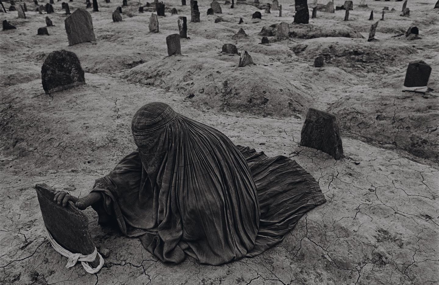 1996 - Afghanistan Unendliches Leid Auf einem Friedhof in Kabul: Ein Fetzen Stoff markiert jenes Grab, das ihr so wichtig ist. Die verschleierte Frau hat ihre Hand auf den Stein gelegt. So fühlt sie sich in ihrer Trauer für einen Augenblick verbunden mit dem Verstorbenen. Es ist ihr Bruder, der in der ausgetrockneten Erde begraben liegt. Er starb durch eine Rakete der Taliban. Eine ganze Generation von Menschen hat in Afghanistan nie etwas anderes als kriegerische Auseinandersetzungen erlebt. Sie prägen das Land seit 1978 – und bis heute. Für dieses und weitere Bilder wird der amerikanische Kriegsreporter James Nachtwey ein Jahr später beim „World Press Photo Award“ ausgezeichnet.