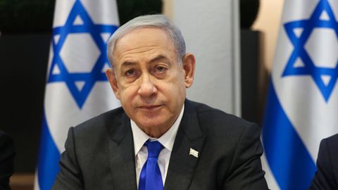 Premier Benjamin Netanjahu sitzt vor mehreren Flaggen von Israel